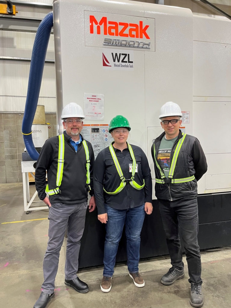 Former Wenzel machinist Sydney Stagg stands in front of a Mazak CNC machine with colleagues