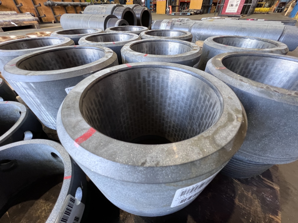 A flow restrictor component sitting atop a pallet. Tungsten carbide tiles can be seen lining the inner wall. 